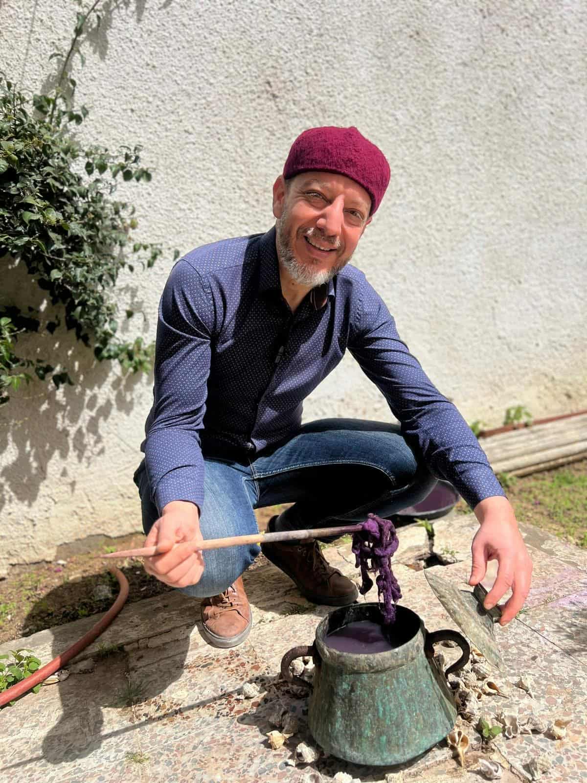 Mohamed Nouira holding a Murex shell, sunlight filtering through leaves onto his face