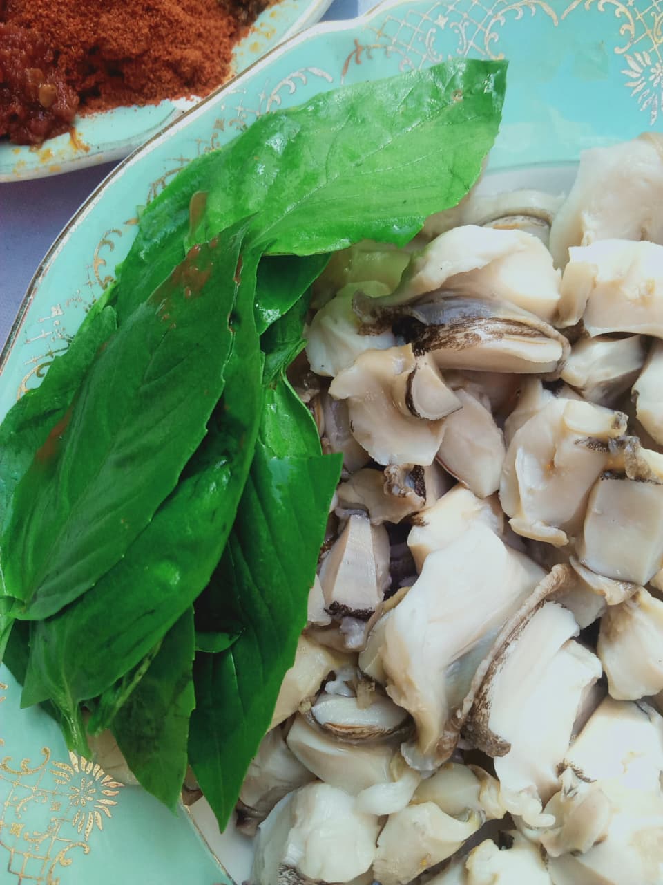 Raw Murex tissue with fresh basil, prepared for ritual or culinary use